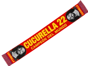 Bufanda de Cucurella 22 roja con el nombre en amarillo, la frase Campeón del mundo y dos fotos en blanco y negro